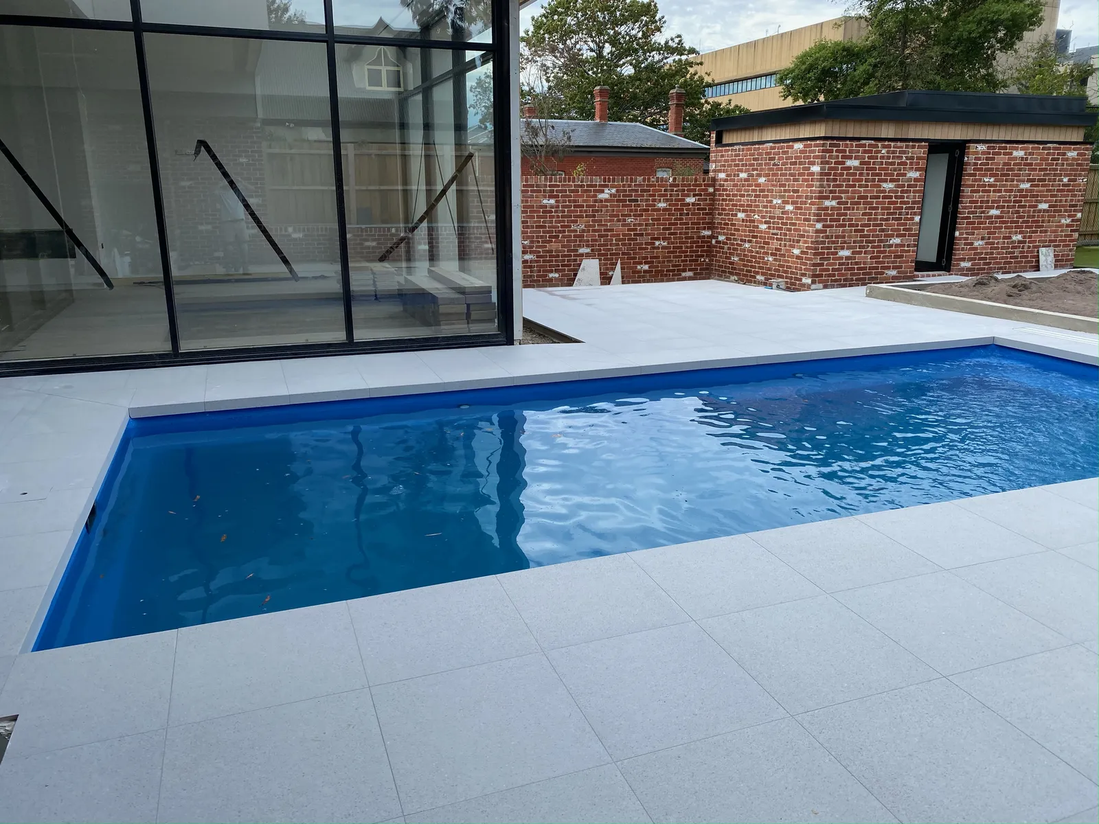 Inground pool surrounded by large-format white porcelain pavers