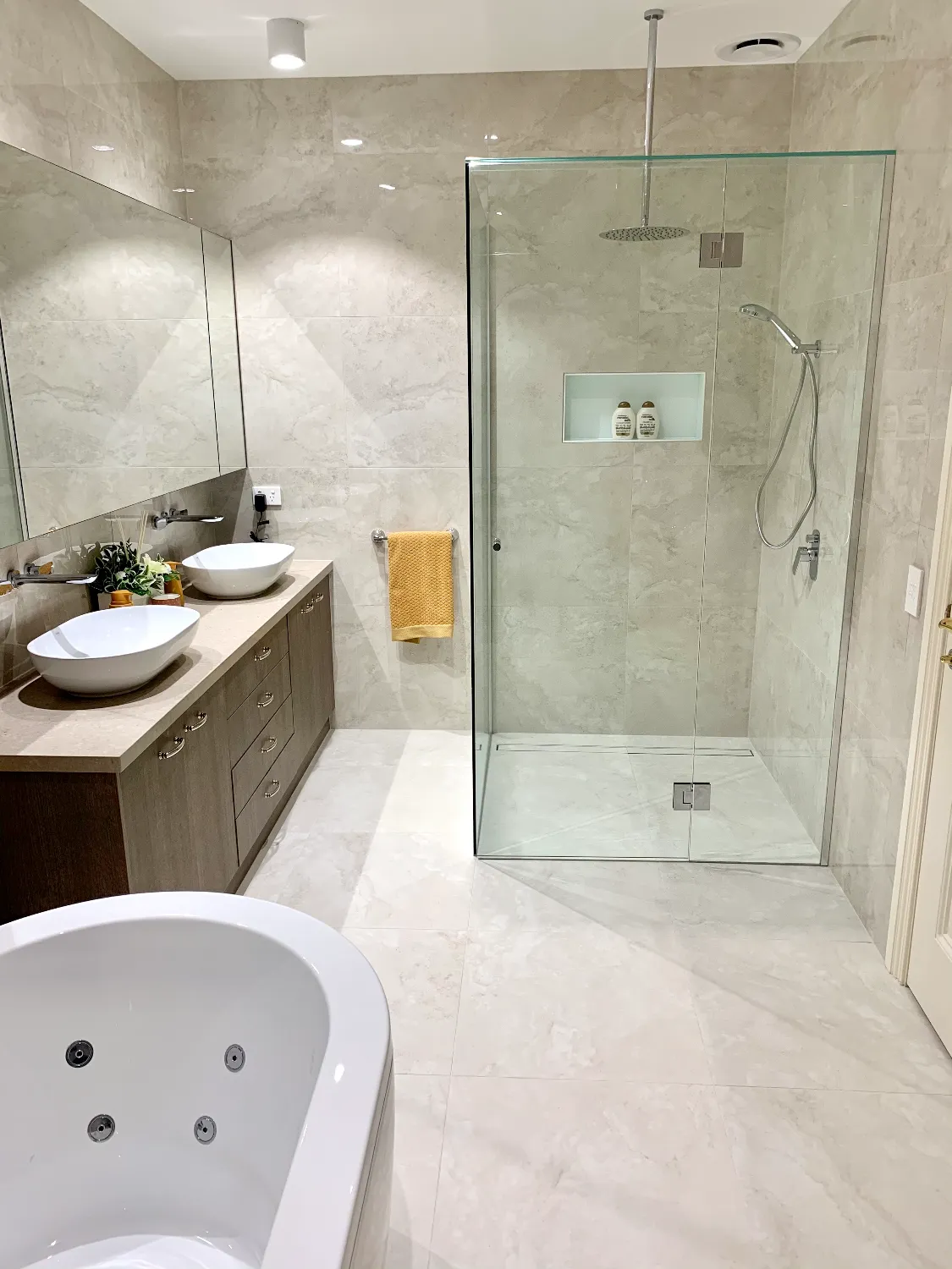 Bathroom with marble-look porcelain tiles, frameless walk-in shower with niche, twin vessel vanity and spa bath