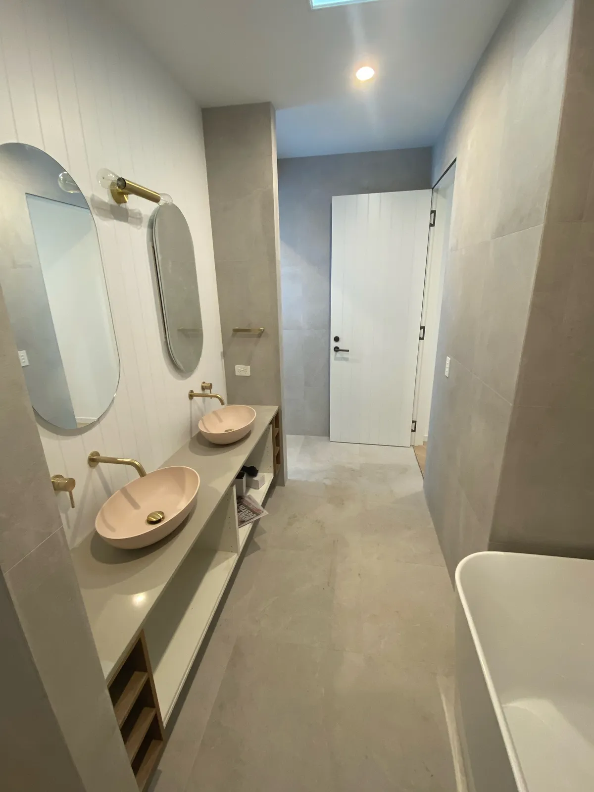Bathroom vanity with twin blush vessel basins, timber detailing and gold tapware
